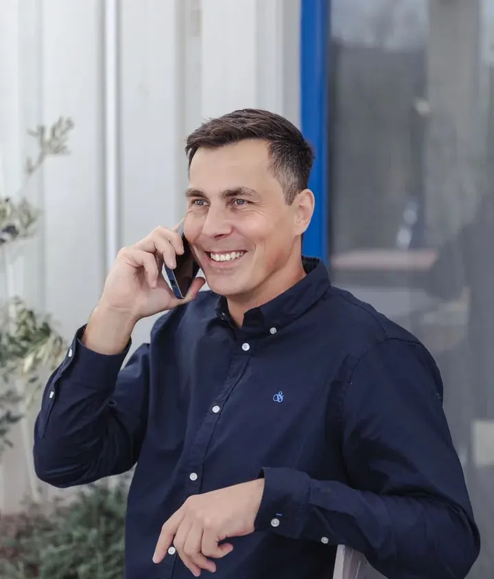 Philipp Enders on the phone outside a café, smiling