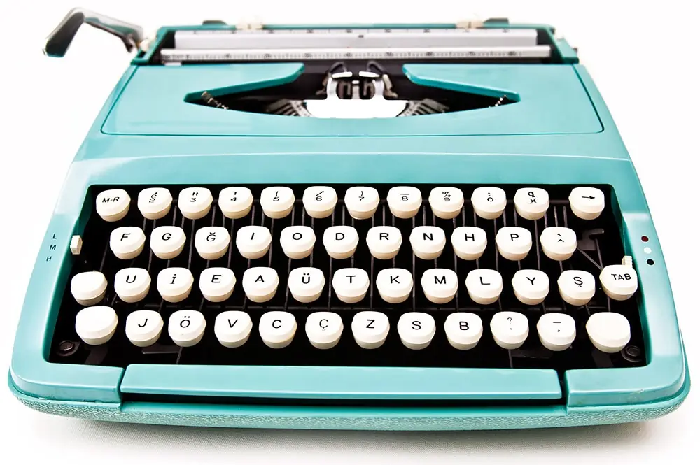 A turquoise typewriter on a white desk